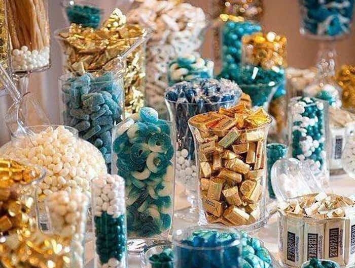 buffet de bonbons des bonbonnieres remplis des bonbons bleus et dores rangues sur une table