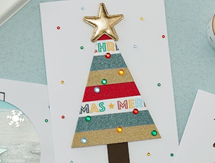 carte noel maternelle en bandes pailletées colorées avec des strass colorés et étoile or sur papier blanc décoration noel maternelle