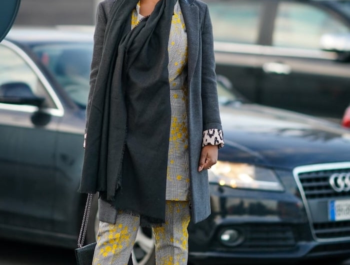 code couleur pantone une femme en tailleur gris et des escarpins jaunes avec des lunettes des soleil devant une voiture