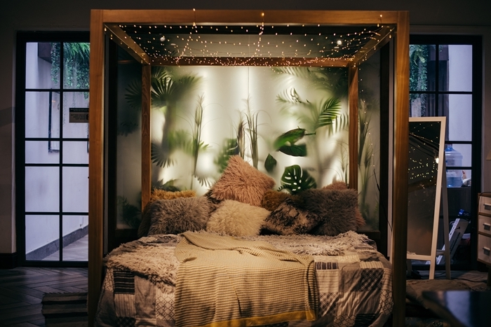 cosy déco chambre cocooning cadre de lit bois guirlande lumineuse mur végétal verre coussin fausse fourrure