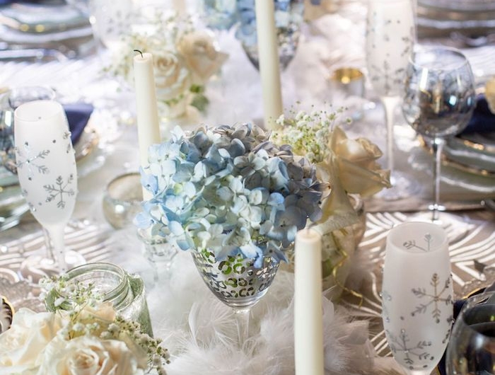 deco nouvelle an avec des roses et des fleurs bleus dans des verres de champagne une decoration de table avec des plumet