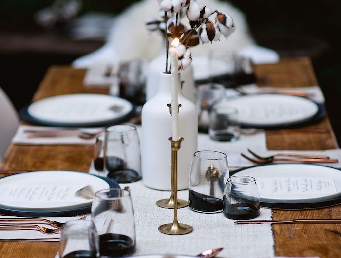 deco nouvelle an minimalistique avec des bougies et des branches de cotton sur une table rustique des couverts en cuivre