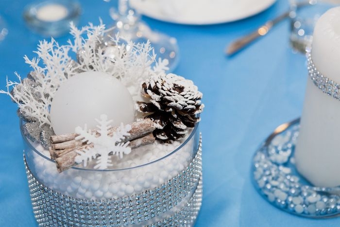 deco table de jour de l an avec des petits details de flocons de fausse neige et cones de pin sur une nappe bleue