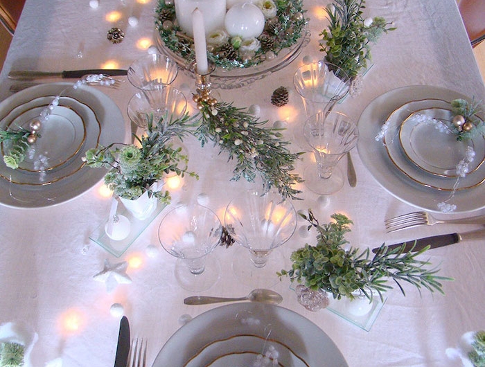 deco table jour de l an avec des elements verts et naturels des lampes de noel et des asiettes aux bordures dores