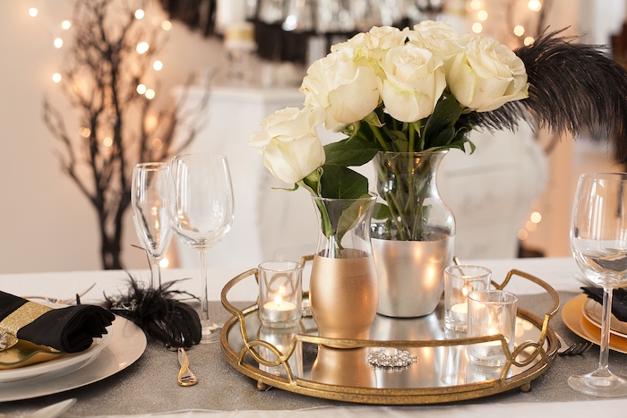 deco table nouvel an avec des elements en or rose serviette noir et un bouquet de roses blanches