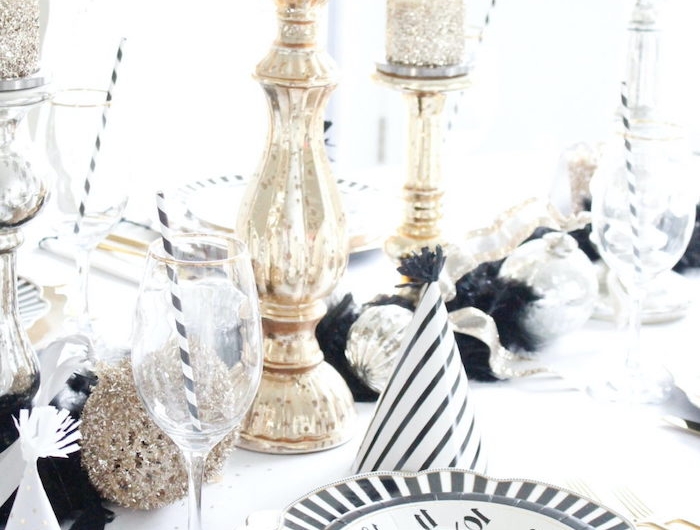 deco table nouvel an avec une assiette en dessin horloge un chandelier doree et guirlande noir
