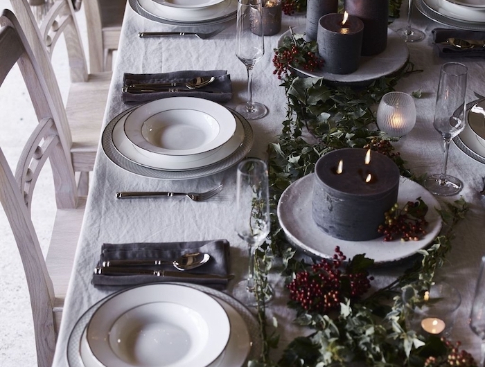 deco table reveillon saint avec une nappe blanche et decorations vertes baies des grandes bougies dans des assiettes