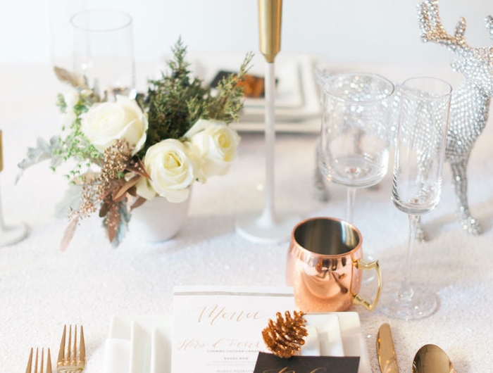 decoration de la table du nouvel an avec des fleurs blanches et des elementen cuivre un cerf en cristaux decratif