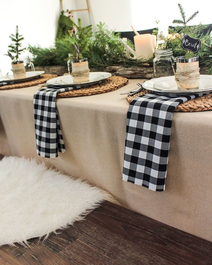 decoration de table pour noël avec des serviettes imprimées en carreaux noir et blanc des branches de sapin et des napperons en paille