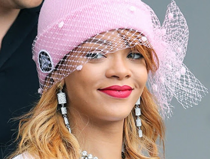 rihanna porte un chapeau rose orne d une voile avec des bousles et un colier a signature