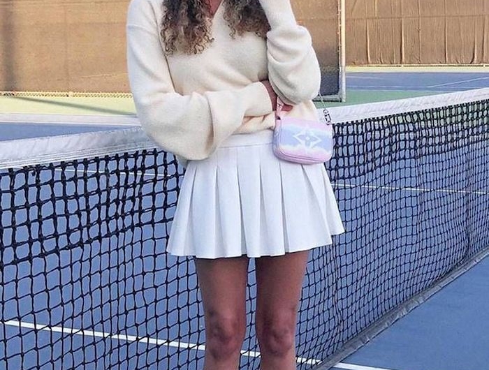 style preppy une fille vetue tout en blanc avec une fedora sur le court de tennis