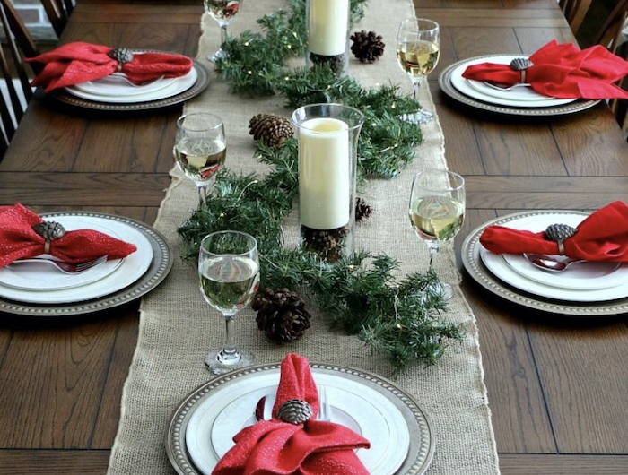 table de noel rouge et blanc avec des element naturels un guirlande verte et cones depin