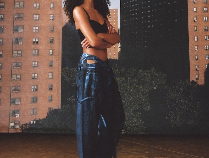 tenue ado fille en style streetwear devznt des grandes batoments avec un jean décontracté top court et cheveux boucle afro