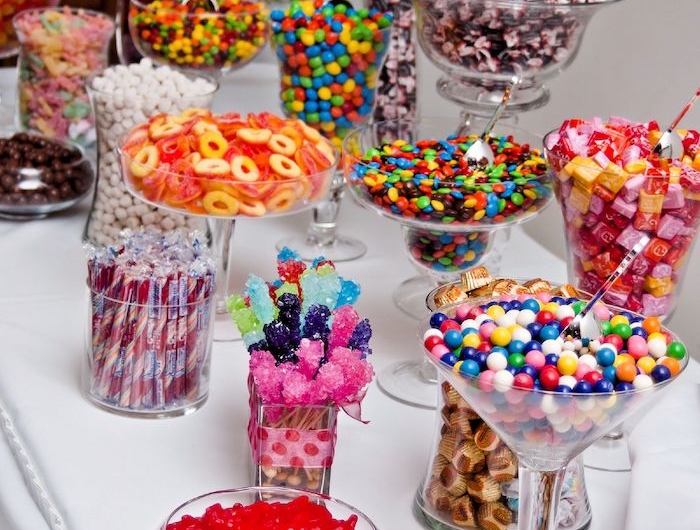 un buffet de candy mutlicolore avec des bonbns gelee de dragees et des bonbonnieres en verre
