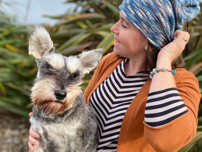 un chapeau bonnet tricotee avec une robe en rayes une femme qui tient un chien