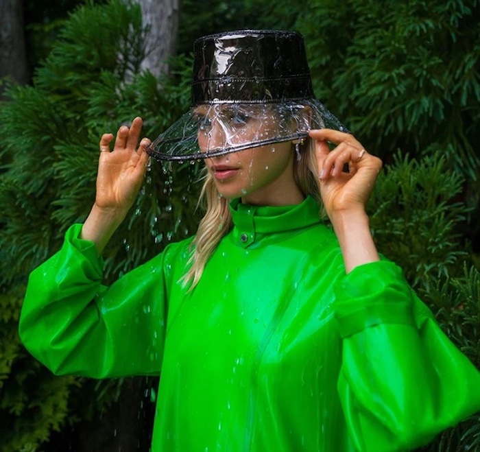 un fedora moderne avec une borde transparente en nylon et une blouse vert vif une fille devant de lverdure