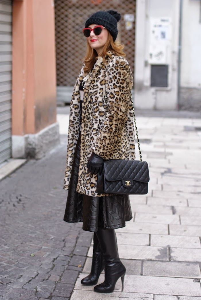 un manteau en imprime leopard avec des bottes en cuir en un beanie noir avec pompon
