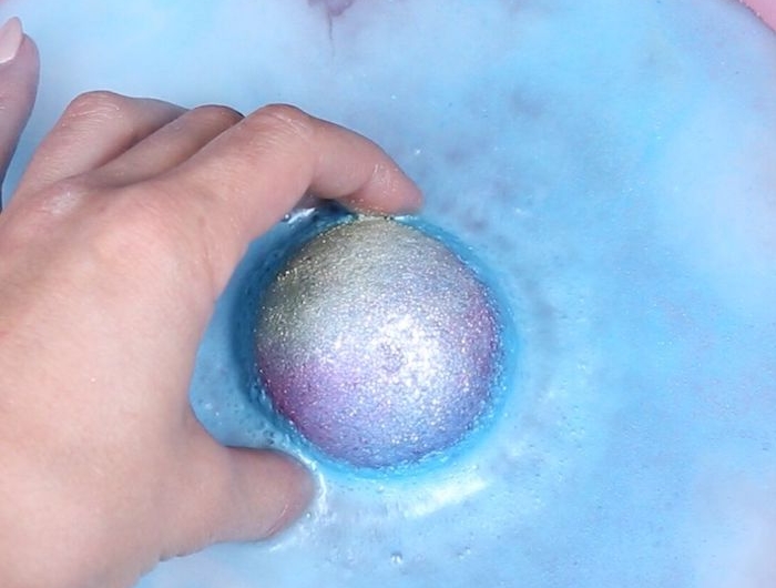 une boule de bain en pailettes qui se fonde soluble dans l eau tenu par une main bombe de bain maison