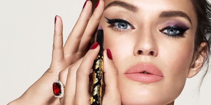 une femme aux yeux bleus qui se fait de maquillage avec un eye liner et des ongles en rouge