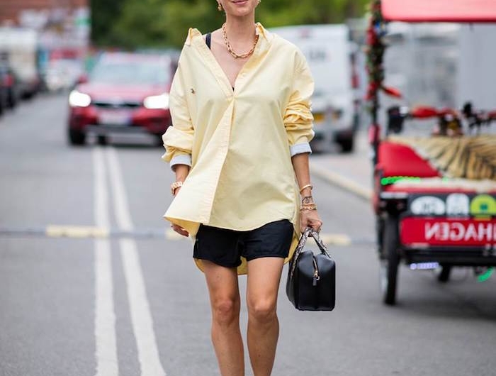 une femme dans la rue avec une chemisier jaune et un pantalon court les couleurs dans la mode