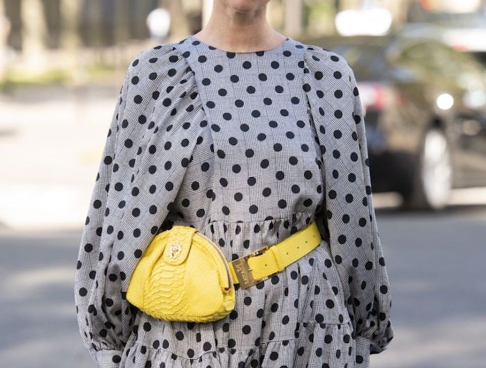 une femme vetue en robe gris a pois et une sacoche jaune pantone 2021