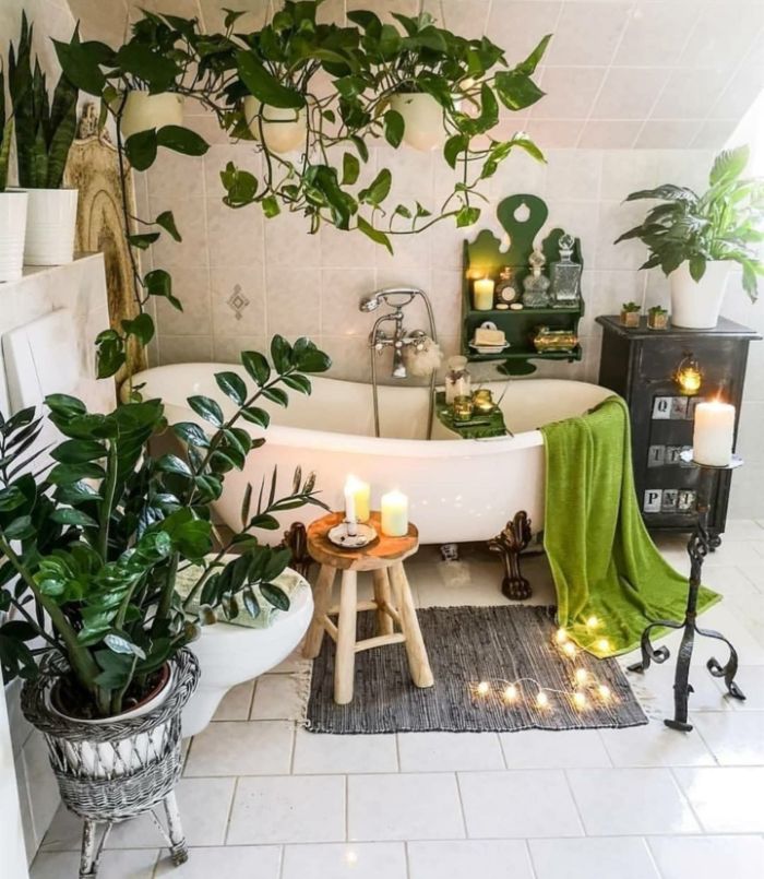 aménagement salle de bain cocooning avec plusieurs plantes vertes salle de bain carrelage sol et murs bougies guirlande lumineuse autour d une baignoire blanche