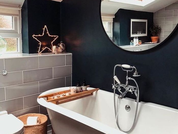 baignoire blanche dans salle de bain noire miroir rond panier tressé table plteau service bois ambiance cosy