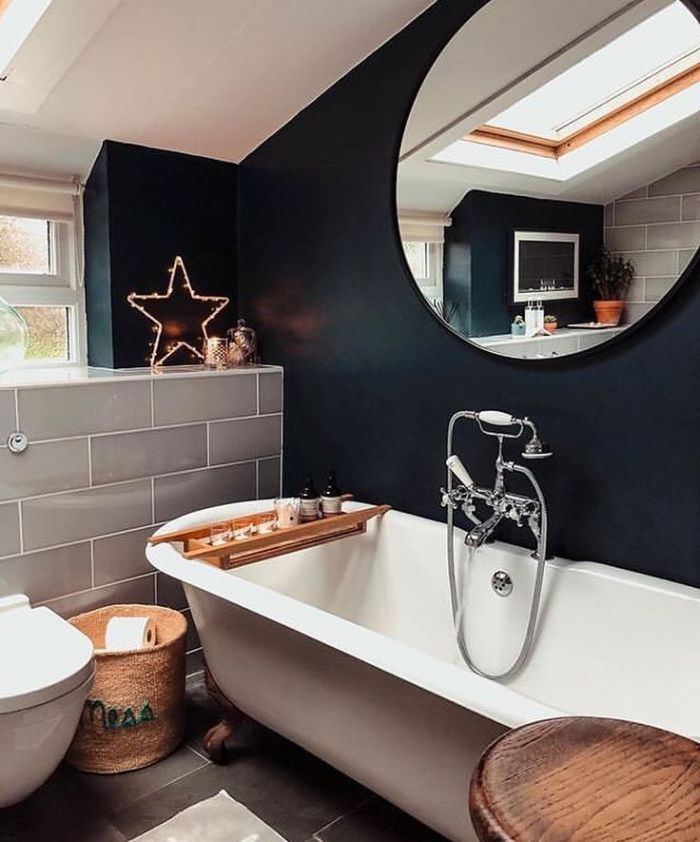 baignoire blanche dans salle de bain noire miroir rond panier tressé table plteau service bois ambiance cosy