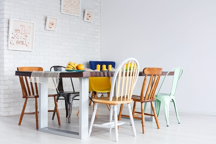 chaise colorée salle à manger table manger bois et blanc cadre mur briques blanches bougies jaunes
