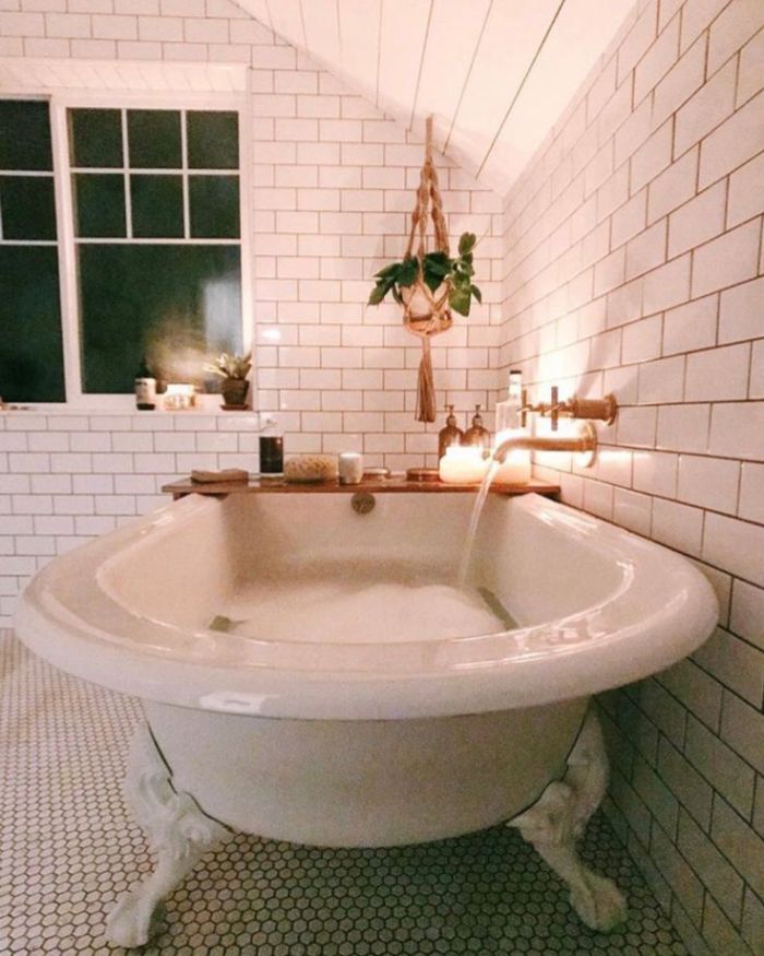 deco salle de bain blanche avec baignoire blanche et plantes suspendues macramé robinetterie en laiton bougies