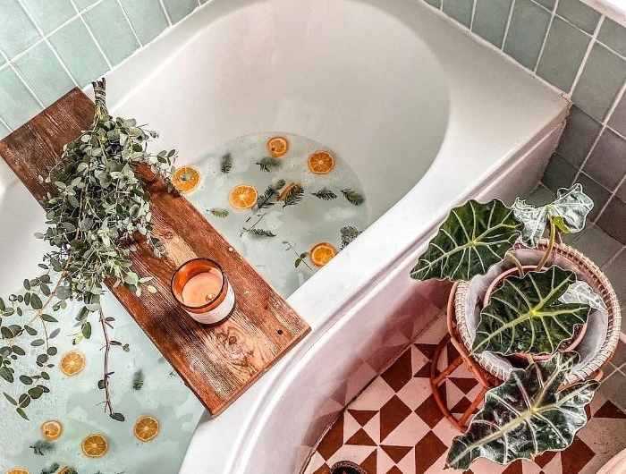 deco salle de bain cocooning avec baignoire blanche carrelage jaune moutarde et blanc pont de baignoire bain aux oranges laurier brins de pin plantes vertes d intérieur