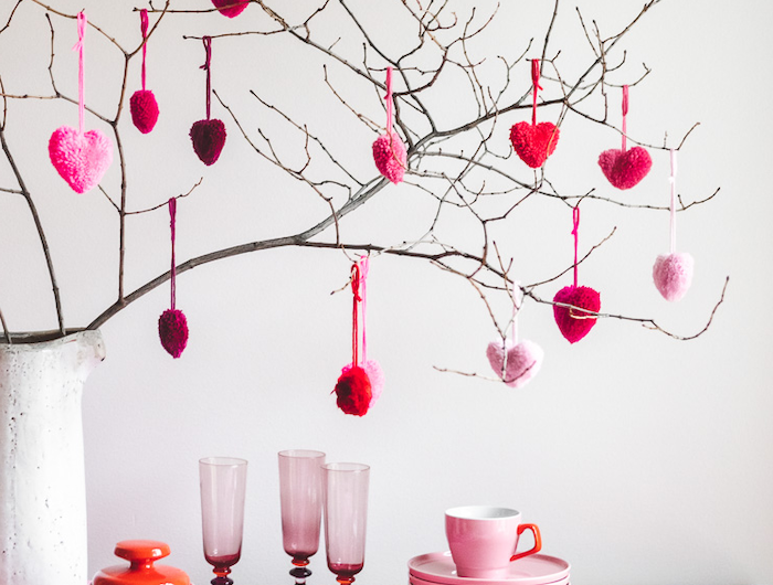 des petites coeurs décoratifs susprendus d une branche une table a nappe rose avec des couverts et des assiettes jpg