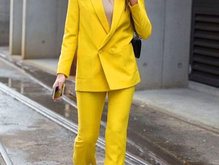 ensemble tailleur femme chic en couleur jaune illumineuse pantone 2021 des bottes noires et lunette tintes