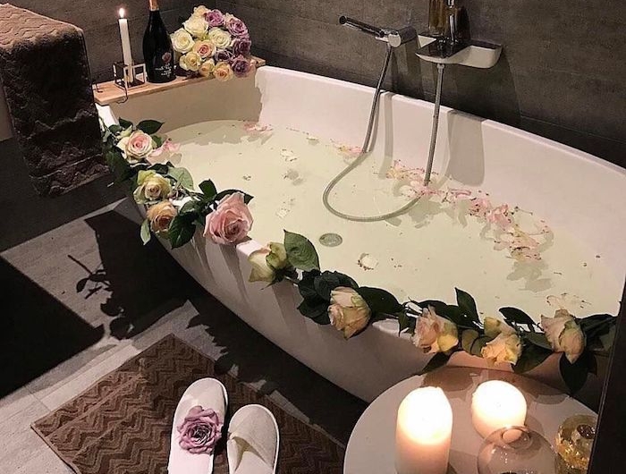 idée saint valentin une baignoire avec des fleurs deux bougies allumés sur une table basse