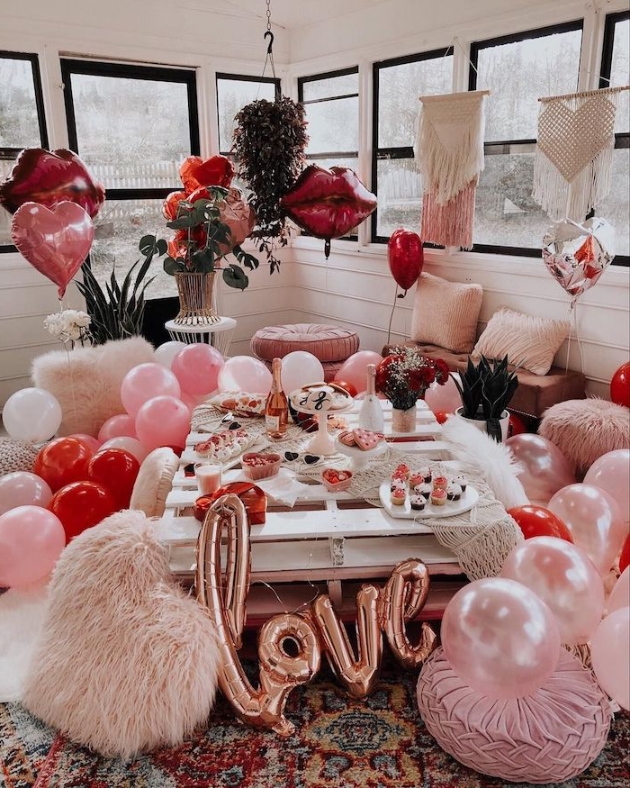 idée surprise saint valentin une salle de séjour décorée de ballons et des coussins roses