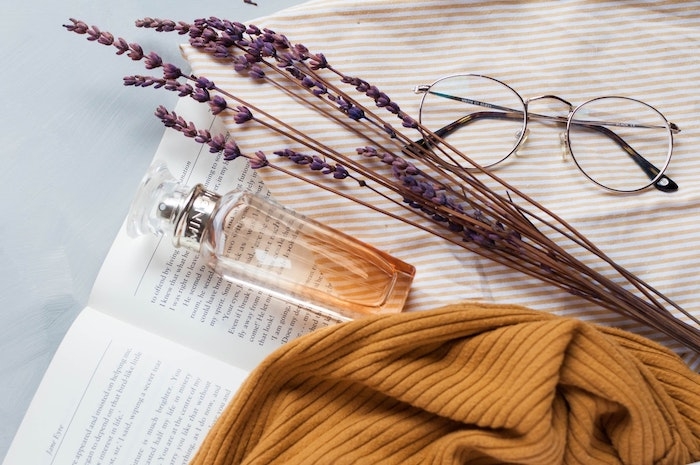 joli flacon de parfum en verre pose sur un livre ouvert lunette de vue hypi
