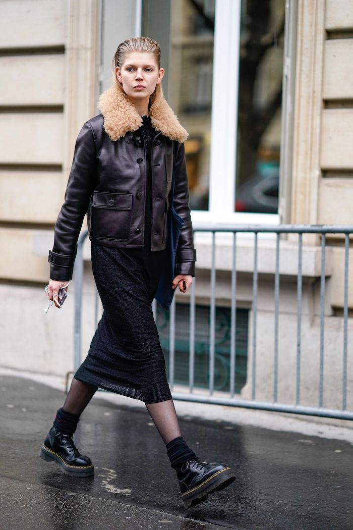 look doc martens avec une veste en cuir et col au fourrure jupe mi longue et un collant noir