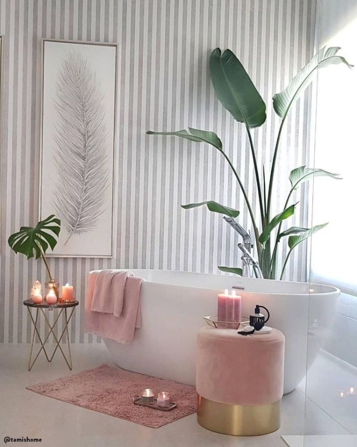 modele salle de bain avec baignoire blanche accents rose poudré tabouret tapis plaid rose plantes vertes bougies parfumées