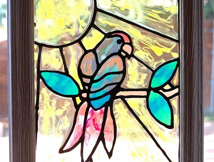 peinture sur verre avec un tableau encadré un perroquet sur branche dessiné au fond jaune