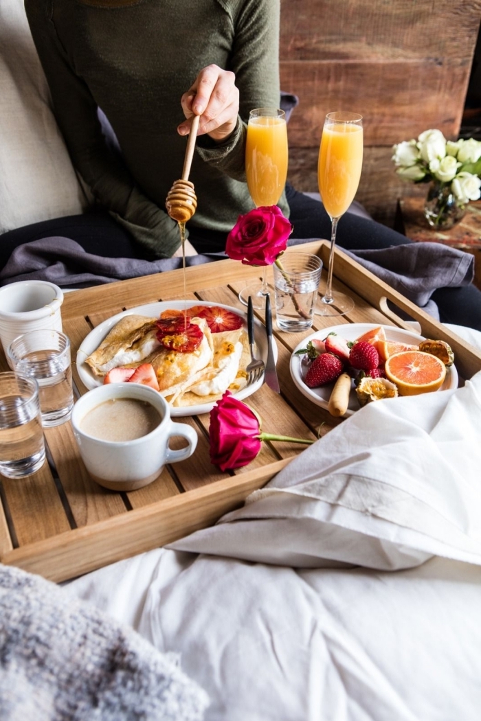 petit déjeuner au lit plateau bois tasse de café verre eau rose jus de fruits assiettes fruits