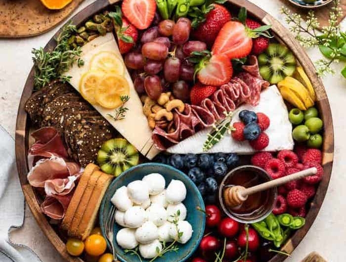 plateau de charuterie avec une abondance des fruits et des legumes et des noix sur une table avec une nappe dans deux bols