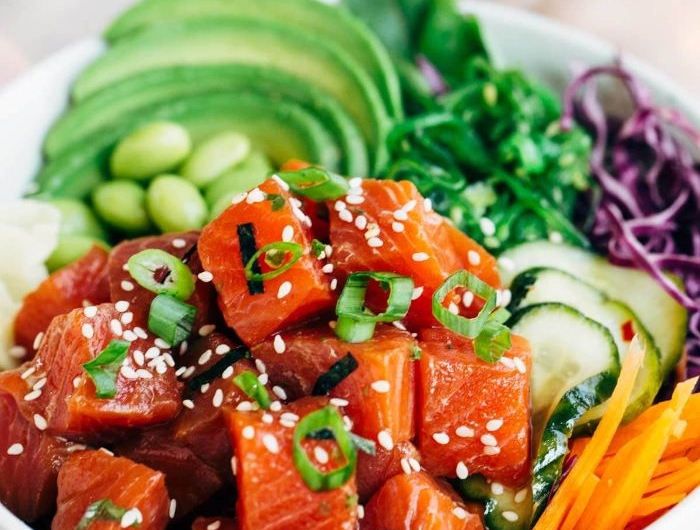 recette bowl saumon avec multitude de legumes frais carottes concombre chou rouge tranches d avocat et feuilles verdures