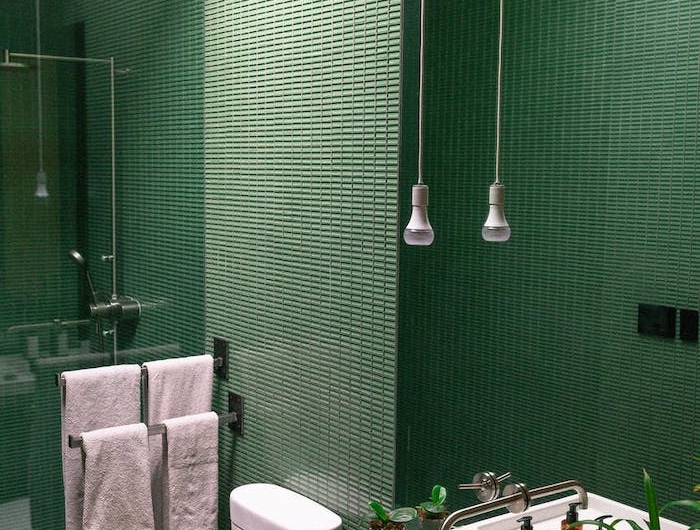salle de bain avec un carrelage mosaique vert et deux lampes suspendus