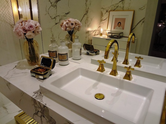 salle de bain avec un lavabo doree et une vase a fleurs a coté