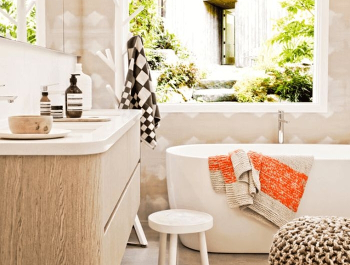 salle de bain bois avec carrelage sol gris baignoire blanche mur blanc et beige pouf gris tapis tressé