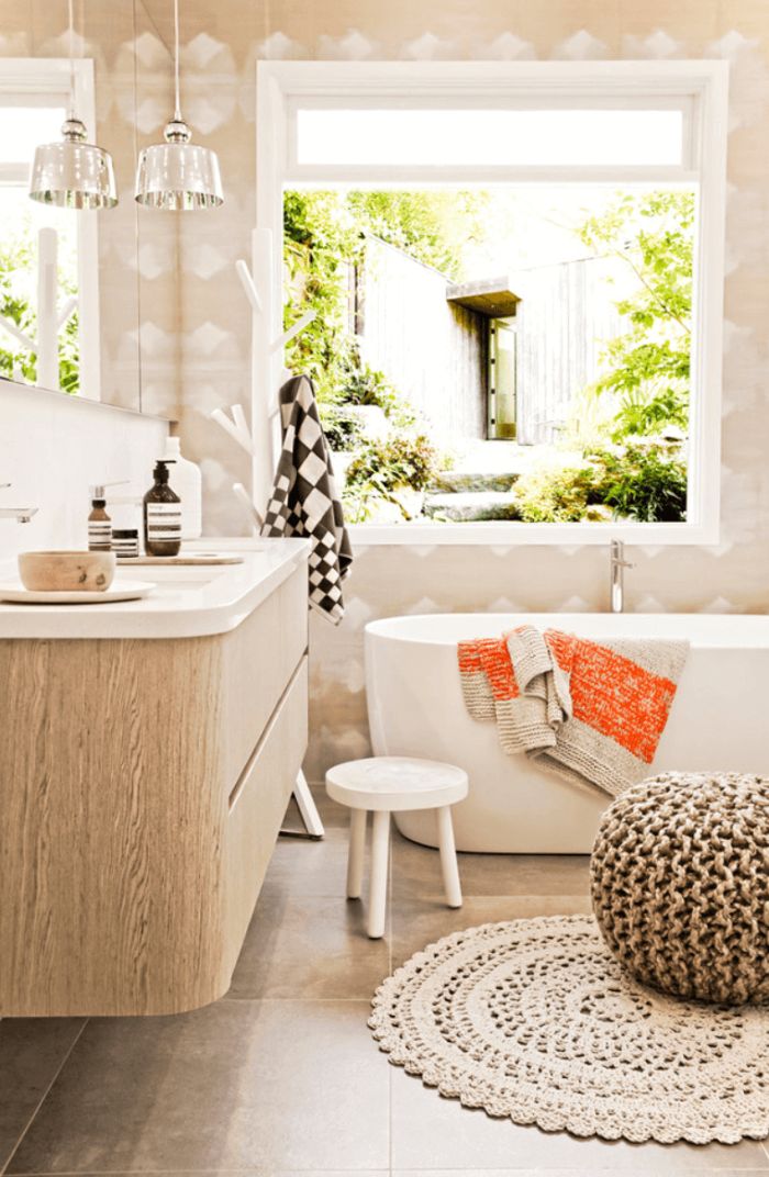 salle de bain bois avec carrelage sol gris baignoire blanche mur blanc et beige pouf gris tapis tressé