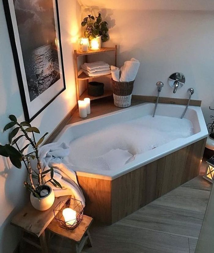 salle de bain bois et blanc avec lumière tamisée bougies plantes vertes et habillage baignoire bois