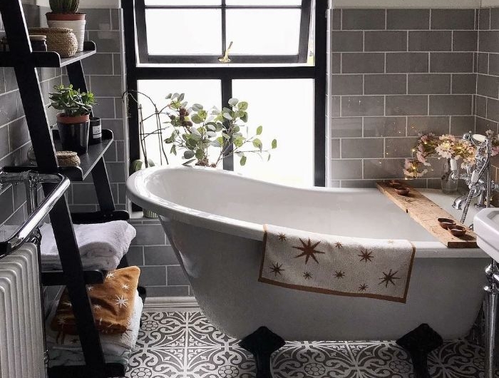sol carreaux de ciment murs revêtus de carrelage gris étagère salle de bain de bois baignoire blanche sur pieds noires