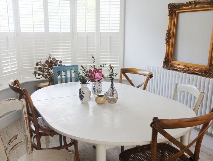 table ovale bois blanc chaise deco bois foncé cadre vide chaise bleu pastel vase verre fleurs séchées