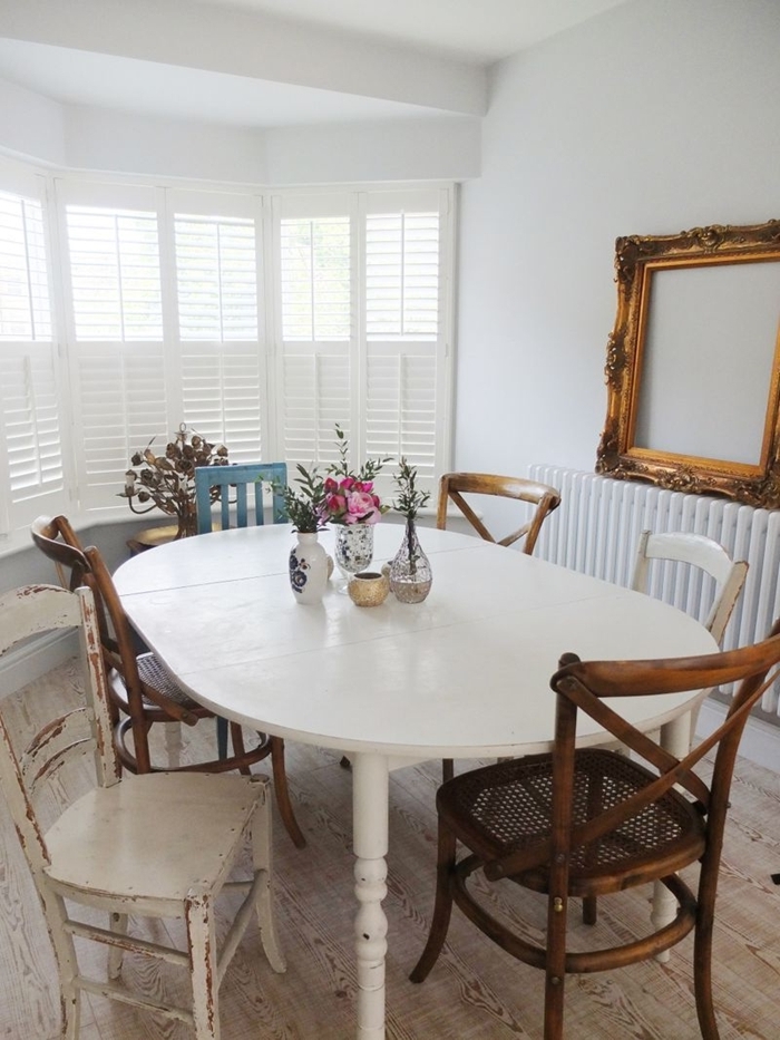 table ovale bois blanc chaise deco bois foncé cadre vide chaise bleu pastel vase verre fleurs séchées